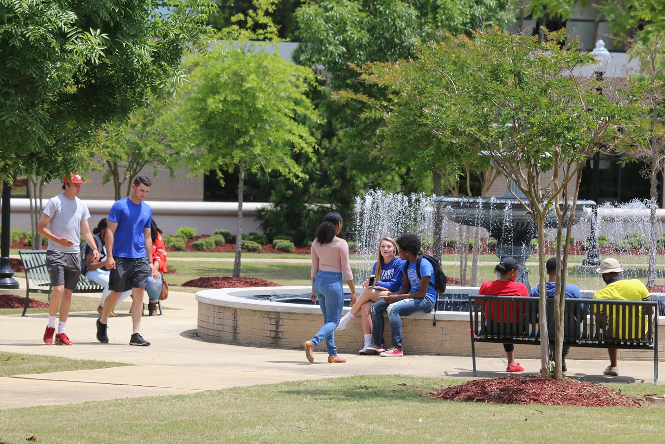 Multiple students moving around campus near the fountain