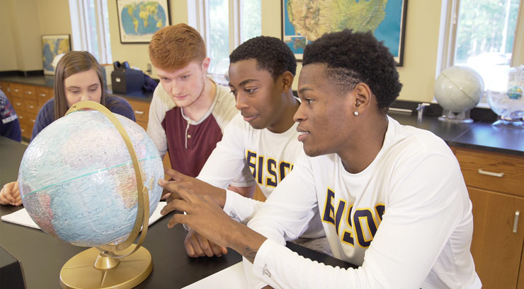 Three male and one female student observing a globe