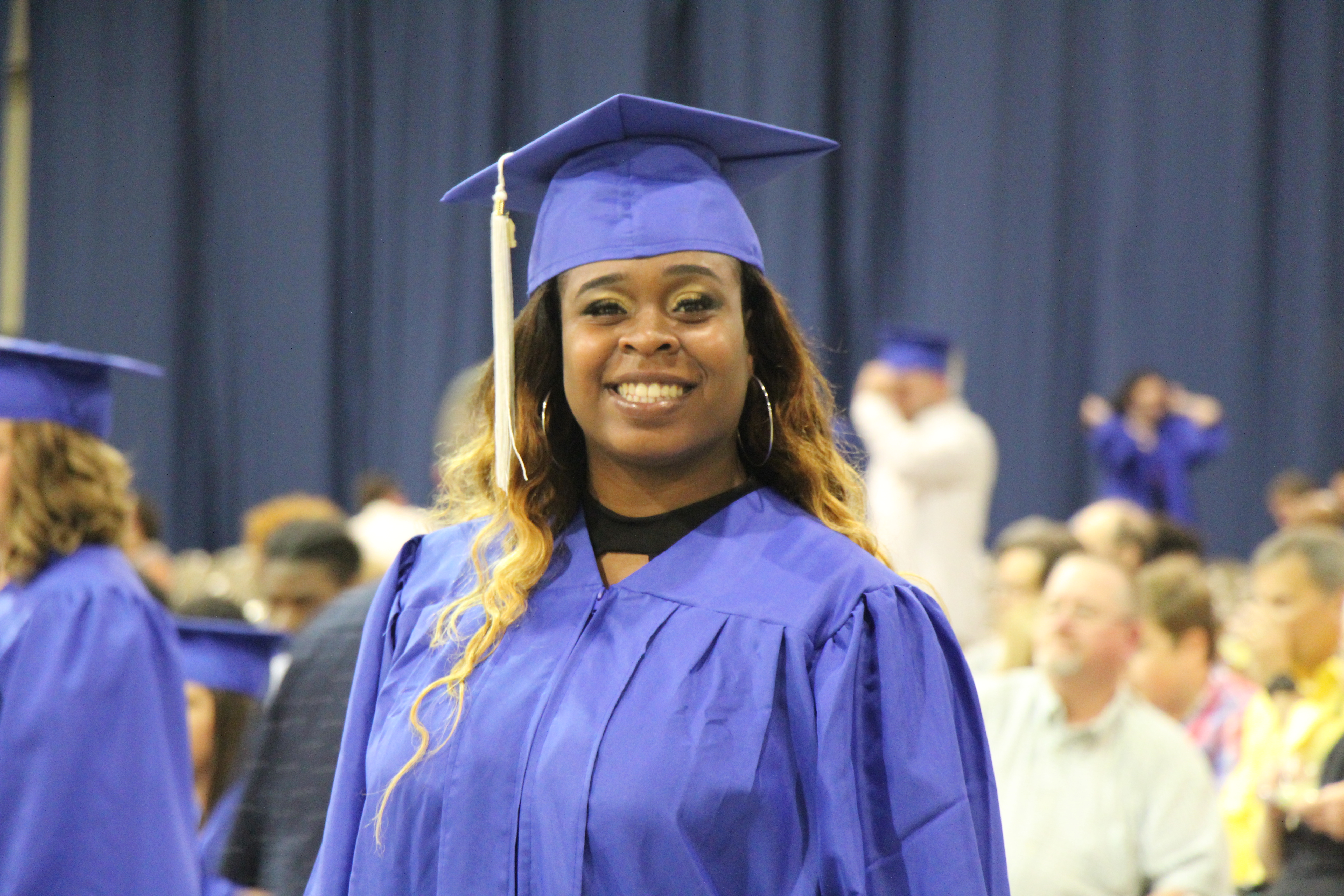 Female in graduation cap and gown smiling at the camera